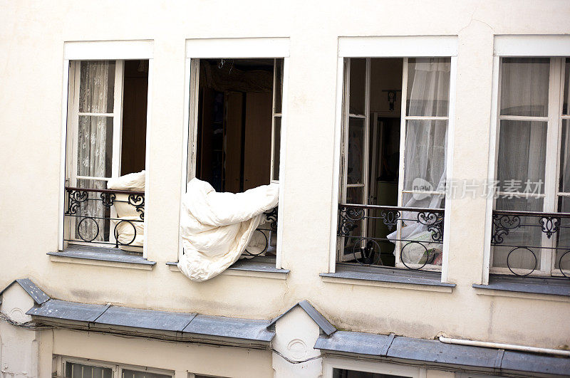 法国，巴黎:羽绒被/被子在敞开的窗户里晾晒